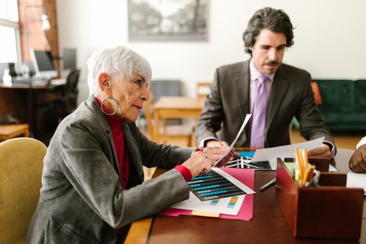 Colleagues discussing documents at a work desk in an office environment.